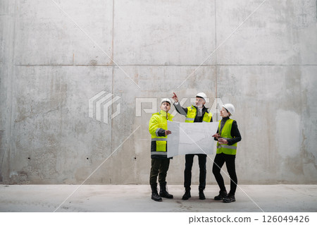 Team of engineers and construction workers reviewing blueprints, building site. 126049426