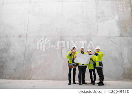 Team of engineers and construction workers reviewing blueprints, building site. Team of engineers and construction workers reviewing blueprints, building site. 126049428