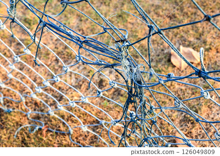 Rope knots are used to repair weathered and tangled green nets. 126049809
