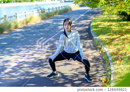 A cool woman stretching on a road in the sunlight, warm-up, splits, hip joints 126049821