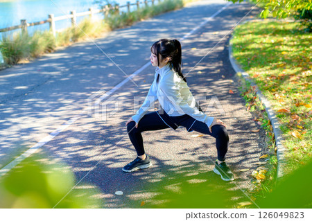 A cool woman stretching on a road in the sunlight, warm-up, splits, hip joints 126049823