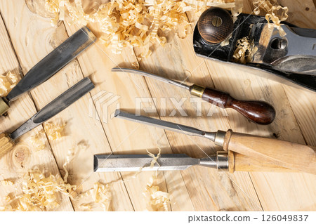 Top view of a traditional carpenter tools and wood shavings lying on wooden planks 126049837