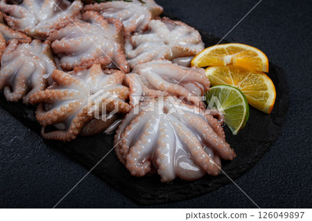 Fresh baby octopus, on black slate, with lemon and greenery, top view, no people, Fresh baby octopus, on black slate, with lemon and greenery, top view, no people, 126049897