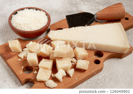 Freshly sliced and grated cheese, parmesan cheese, on a wooden chopping board, rustic style, no people 126049902