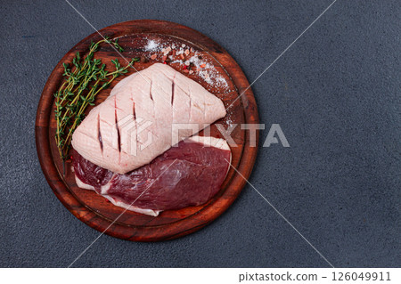 Fresh raw duck breasts, on a wooden chopping board, with herbs and spices, no people 126049911
