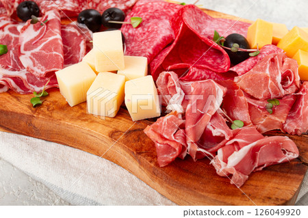 Assorted, sliced meat appetizer, prosciutto, salami and ham, with cheese and olives, on a wooden board, breakfast, top view, close-up, no people, Assorted, sliced meat appetizer, prosciutto, salami and ham, with cheese and olives, on a wooden board, breakfast, top view, close-up, no people, 126049920