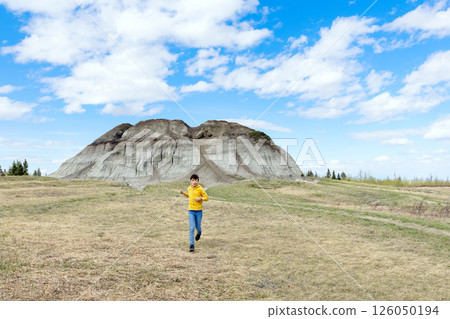 Teen boy is running in badlands, walk in the spring nature. Teen boy is running in badlands, walk in the spring nature. 126050194