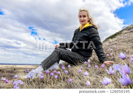 Woman is enjoying first spring flowers Crocuses in hills. Woman is enjoying first spring flowers Crocuses in hills. 126050195
