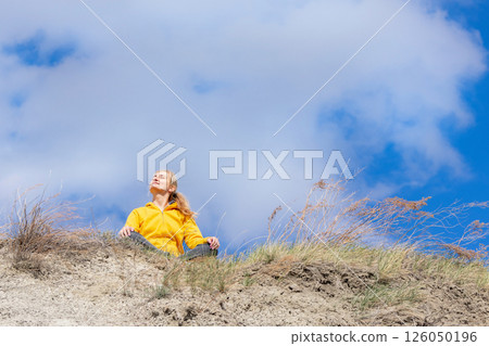 Woman is sitting on the hill and connecting with nature under the sky. 126050196