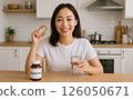 微笑的女人在家中廚房用水服用營養補充劑,體現了健康和日常自我照顧。 微笑的女人在家中廚房用水服用營養補充劑,體現了健康和日常自我照顧。 126050671
