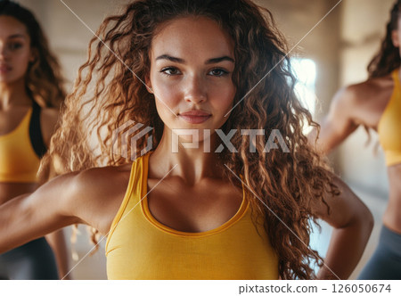 A woman with long, curly hair intensely participates in a high-energy dance class among others. 126050674