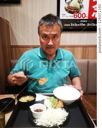 A man eating a limited-edition pork cutlet set meal at a newly opened fast food restaurant in front of Toride Station 126051160