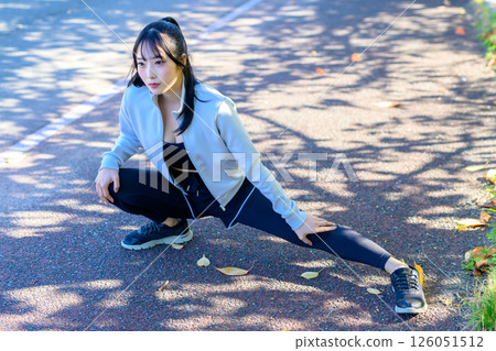 一位酷酷的女人在河邊的人行道上伸展雙腿,彎曲和伸展,節食,散步,鍛煉,修剪 一位酷酷的女人在河邊的人行道上伸展雙腿,彎曲和伸展,節食,散步,鍛煉,修剪 126051512