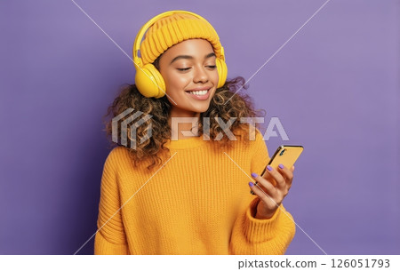 A Young Woman Smiles as She Listens to Music on Her Smartphone 126051793