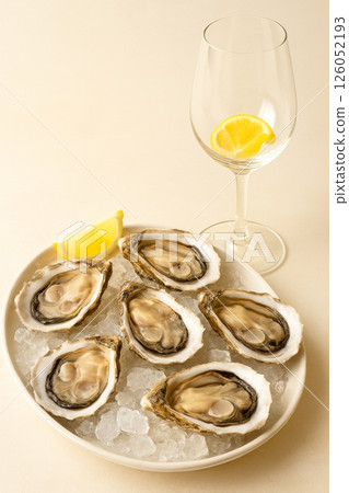 Fresh Oysters Served on Ice With Lemon and a Glass of White Wine in a Casual Setting 126052193