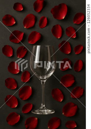 Elegant Glass Surrounded by Red Rose Petals on a Dark Background Suited for Romantic Occasions 126052334