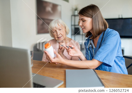 Nurse explaining elderly woman patient medications on laptop in medical clinic or in hospice care Nurse explaining elderly woman patient medications on laptop in medical clinic or in hospice care 126052724