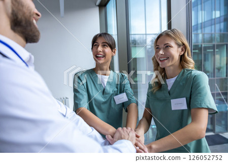 Group of doctors holding hands together and looking positive and smiling 126052752