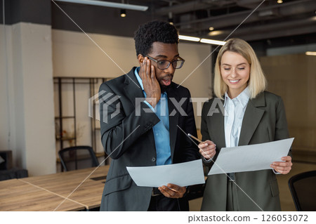 African american lawyer looking surprised while checking the documents his colleague showing him 126053072