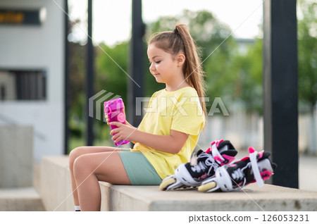 Little girl with roller-skates drinking water outdoors Little girl with roller-skates drinking water outdoors 126053231