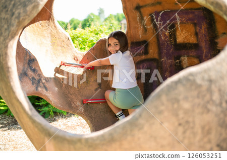 Little girl playing actively in playground enjoying fun outside on summer day Little girl playing actively in playground enjoying fun outside on summer day 126053251