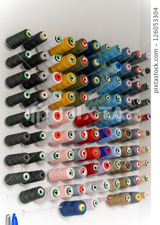 Many colorful threads and balls of wool in a row on the wall 126053304