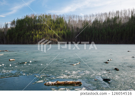 Rocky Cliff Above Frozen Lake with Pine Trees in Early Spring 126054516