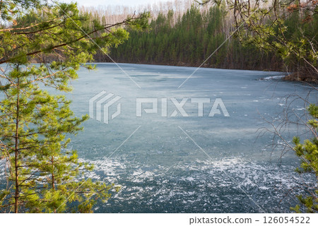 Rocky Cliff Above Frozen Lake with Pine Trees in Early Spring 126054522