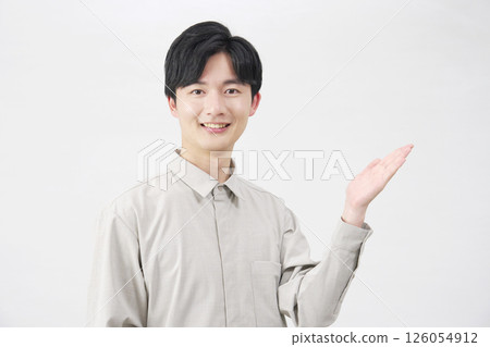 Man in his 20s pointing to the right with his palm, white background 126054912