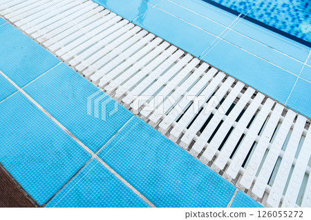 Modern swimming pool design with textured tiles and white slats enhancing aesthetics and safety features 126055272