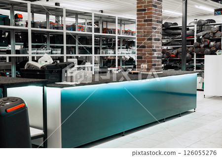 Modern interior design of a busy retail store featuring a sleek counter with storage and organized inventory on shelves Modern interior design of a busy retail store featuring a sleek counter with storage and organized inventory on shelves 126055276