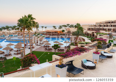 Beautiful resort with pools and palm trees at sunset in a tropical location Beautiful resort with pools and palm trees at sunset in a tropical location 126055359