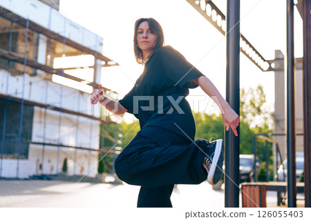 Dancer performs expressive movement outdoors in urban setting during golden hour 126055403