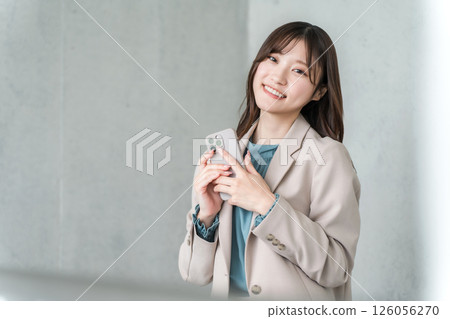 A young Asian businesswoman in a suit operating a smartphone 126056270