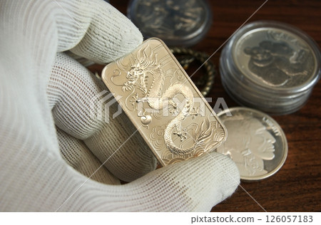 Silver bar with dragon in the appraiser's hand 126057183