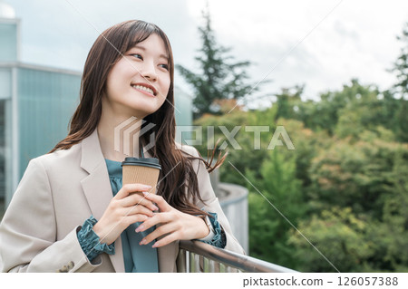 一位身穿西裝的年輕亞洲女性在屋頂上喝咖啡提神 一位身穿西裝的年輕亞洲女性在屋頂上喝咖啡提神 126057388
