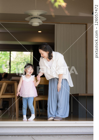 A mother and daughter (child) holding hands relaxing in a garden or a room with a porch Image of the happiness of raising children A mother and daughter (child) holding hands relaxing in a garden or a room with a porch Image of the happiness of raising children 126057472