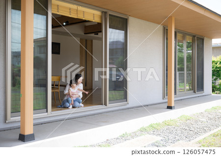 A mother and daughter (child) relaxing in their arms on the porch or veranda. A wide-angle, full-body image of the happiness of raising children 126057475