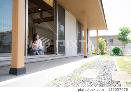 A mother and daughter (child) relaxing in their arms on the porch or veranda. A wide-angle, full-body image of the happiness of raising children A mother and daughter (child) relaxing in their arms on the porch or veranda. A wide-angle, full-body image of the happiness of raising children 126057476