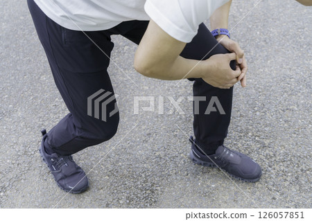 一名年輕男子在跑步時膝蓋疼痛,雙腳緊握膝蓋 一名年輕男子在跑步時膝蓋疼痛,雙腳緊握膝蓋 126057851
