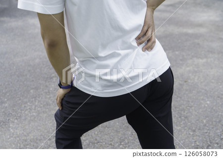 A young man's feet holding his lower back because his lower back hurts while running Lower back pain A young man's feet holding his lower back because his lower back hurts while running Lower back pain 126058073
