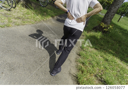 A young man's feet holding his lower back because his lower back hurts while running Lower back pain A young man's feet holding his lower back because his lower back hurts while running Lower back pain 126058077