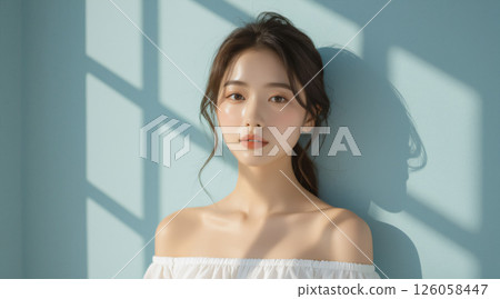 A woman surrounded by soft light by a blue wall 126058447