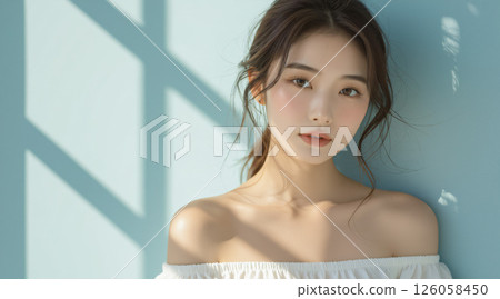 A woman surrounded by soft light by a blue wall 126058450