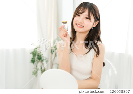 Smiling Asian woman holding a bottle of medicine/supplements 126058897