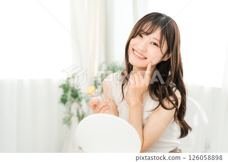 微笑的亞洲女人拿著一瓶藥/補品 126058898