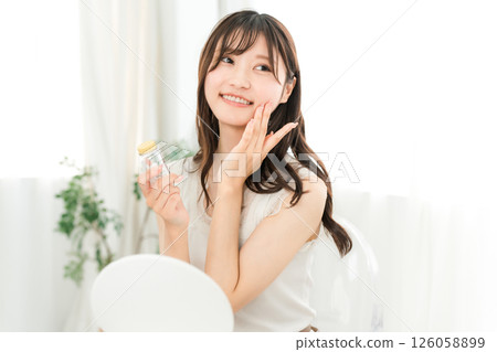 微笑的亞洲女人拿著一瓶藥/補品 126058899