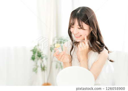 Smiling Asian woman holding a bottle of medicine/supplements 126058900