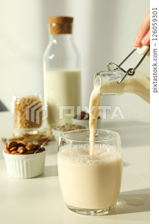 Bottles and glass of alternative milk and herbal ingredients on light background, close up Bottles and glass of alternative milk and herbal ingredients on light background, close up 126059301
