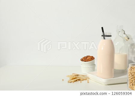 Bottles of alternative milk and herbal ingredients on light background, space for text 126059304